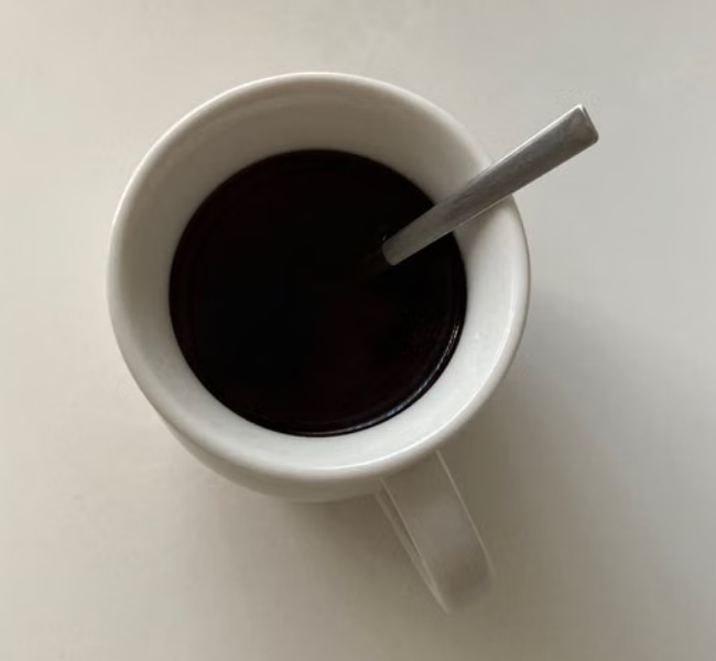 Freshly brewed black drip coffee in a plain ceramic mug