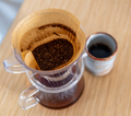 Pour-over coffee brewing beside a plain ceramic mug