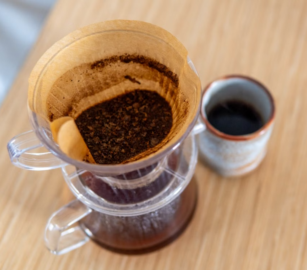 Pour-over coffee brewing beside a plain ceramic mug